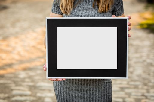 A girl was holding a gray frame with black passepartout without a picture