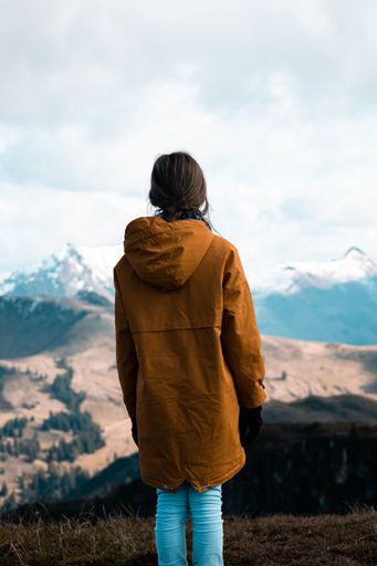 A vertical shot of a girl admiring mountain view from high above hiking in Austria