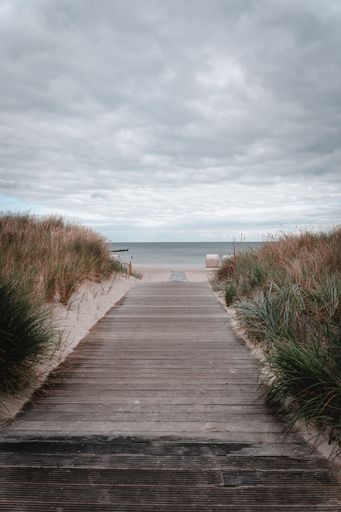 A vertical shot of a wooden path leading up to a beach in Germany on a cloudy day