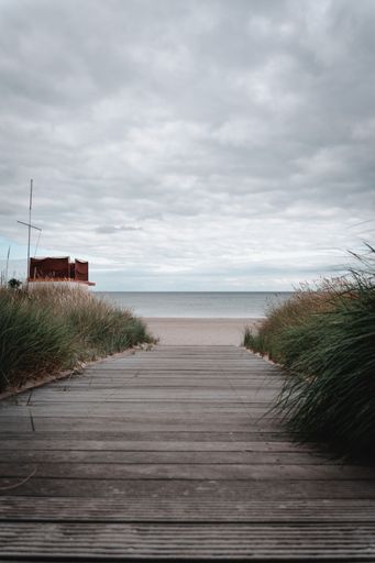 A vertical shot of a wooden path leading up to a beach in Germany on a cloudy day