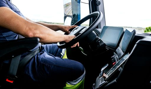 A closeup shot of a man driving a bus from inside