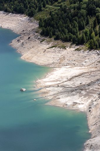 An aerial shot of the coast of the Lake Aussois in France with fir trees in the background