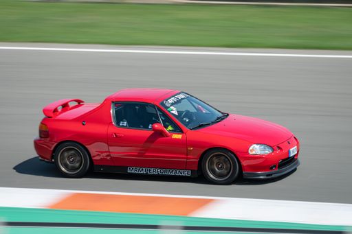 A red Japanese Honda CR-X Del Sol sports car racing around on a competition track