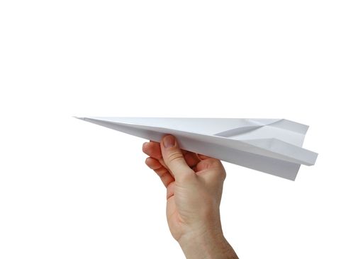 A closeup of a person holding a paper plane isolated on a white background