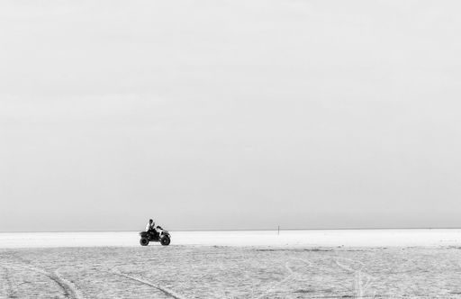 A grayscale shot of a guy riding beach buggy by the sea