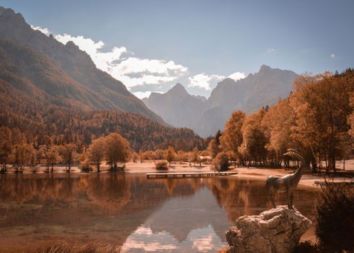 A landscape view of trees by reflecting water under green mountains