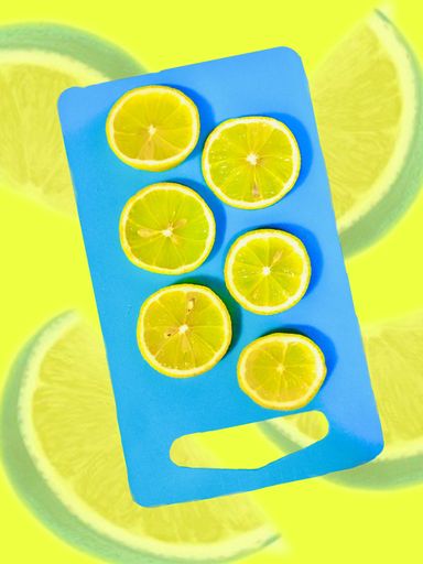 A top view shot of lemon slices on blue cutting board on yellow background