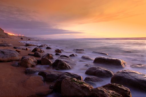 A soft tide covering the rocky beach at sunset at Matadouro beach, Ericeira, Portugal