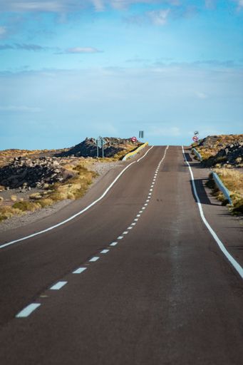 A vertical shot of an asphalt road under blue sky