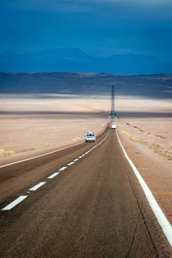 A vertical shot of a highway road in the Atacama Desert under blue, Chile