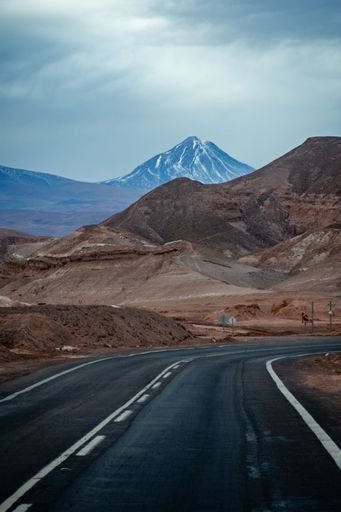 A vertical shot of an asphalt turning road in the Atacama Desert under dark sky in Chile