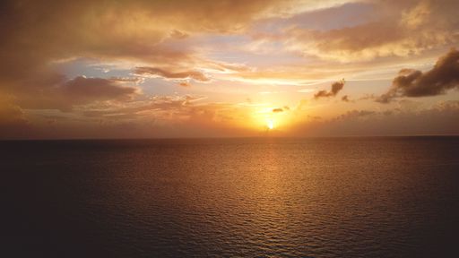 A mesmerizing scene of the Bahamas at orange sunrise with clouds in the sky