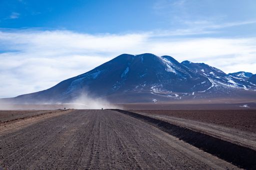 A vertical shot of a road and El Tatio Geyser mountain in the background, Chile under blue sky