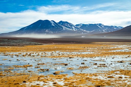 A beautiful view of the El Tatio Geyser over wetland under a blue cloudy sky in Chile