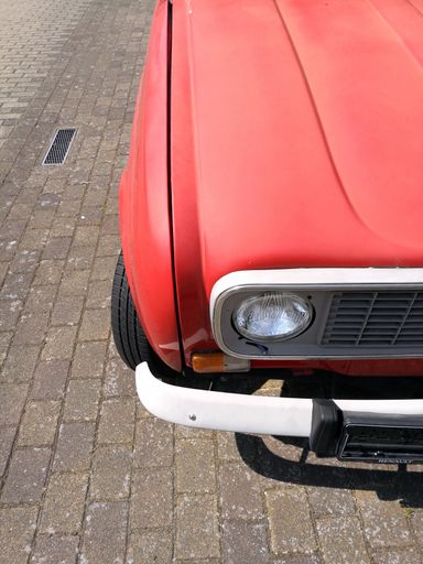 A closeup vertical shot of a red old retro car front light details
