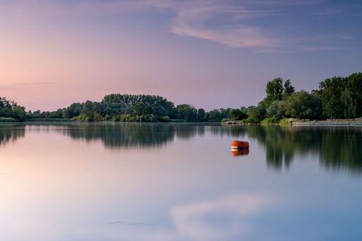 A red buoy and surrounding trees reflected in Giftener see