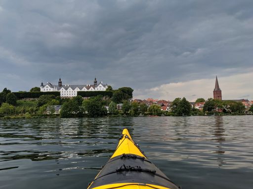 Ploen, schleswig-holstein, Germany, yellow kayak on ploner ploener lake in background plon castle, dark sky with dramatic clouds, river Schwentine