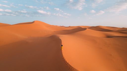 A woman standing on the desert sands under the sun heat