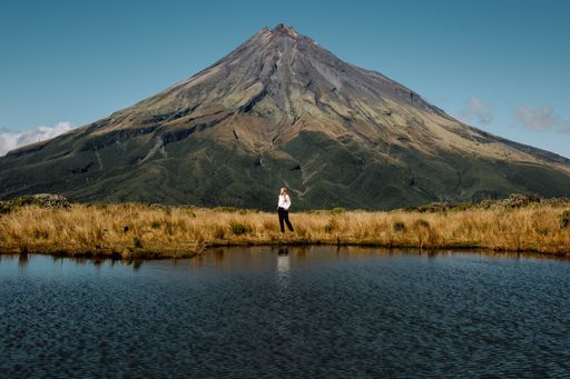 A  young female standing near the high Mount Taranaki, Egmont National Park North New Zealand