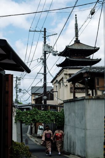 A vertical shot of two young female in kimono walking down the beautiful street