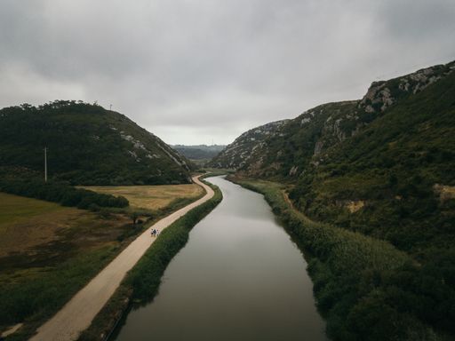 An aerial view of the wide forest river near the road  during the gloomy weather