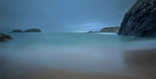 A breathtaking view of the calm see with rock formation in the background, long exposure