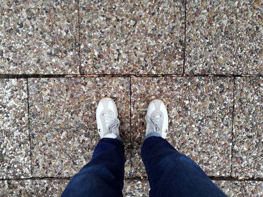 A high angle shot of a person's feet on the ground at daytime