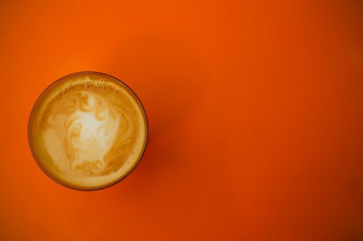 A high angle shot of a glass of coffee on a red surface