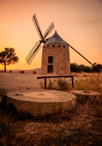 A vertical shot of a stone windmill in the countryside during an orange sunset in rural Alcublas,Spain