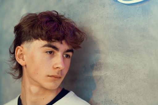 A portrait of a young Caucasian boy with a fresh mullet haircut