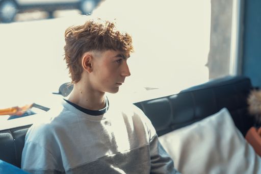 A portrait of a young Caucasian boy with a fresh mullet haircut