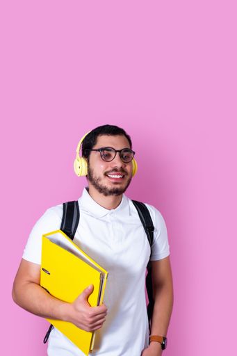 A vertical shot of a Caucasian man wearing headphones and holding a folder