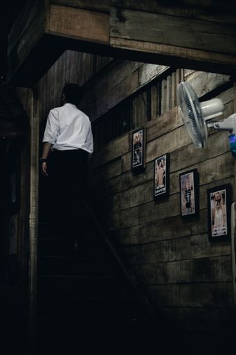 A vertical shot of a male going up a wooden stairs