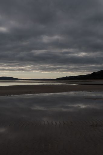A vertical shot of a sea surface in the evening under the cloudy gloomy sky