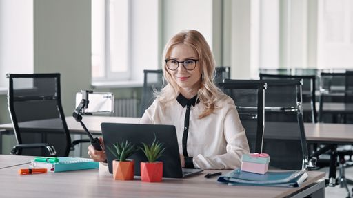 A Blonde Caucasian woman in an office space with a selfie stick in her hand. Ukraine