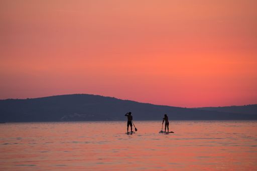A breathtaking view of silhouettes of two people sailing on a SUP at golden pink sunset, Brac Island, Croatia.
Perfect for a background.