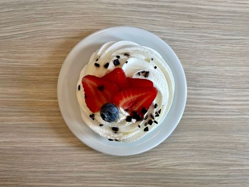 Meringue-based dessert Pavlova with whipped cream and chocolate, strawberry slices and blueberry decoration. Cake is named after the Russian ballerina