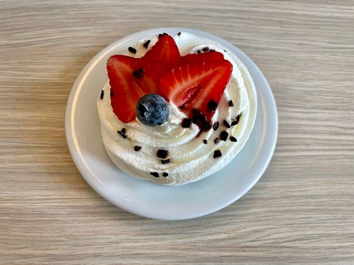 Meringue-based dessert Pavlova with whipped cream and chocolate, strawberry slices and blueberry decoration. Cake is named after the Russian ballerina