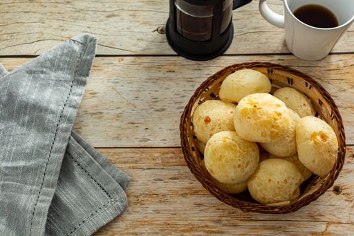 top view of brazilian cheesebread, or 'pao de queijo' with french press coffee maker and mug, over table. copy space
