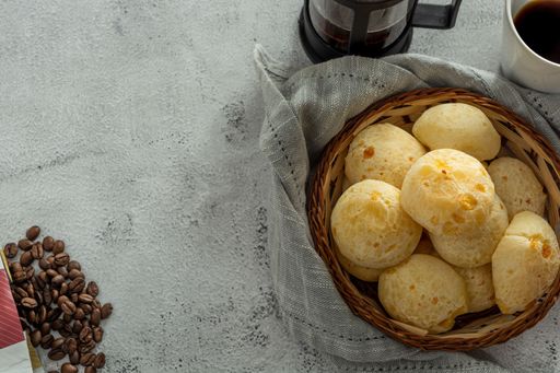 basket with cheese breads, or 'pao de queijo, with coffee items, on a stone table