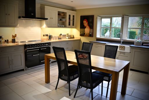 A modern kitchen with tiled floor, gray furniture and wooden table with black chairs