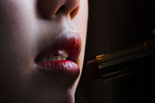 A closeup shot of a woman applying red lipstick