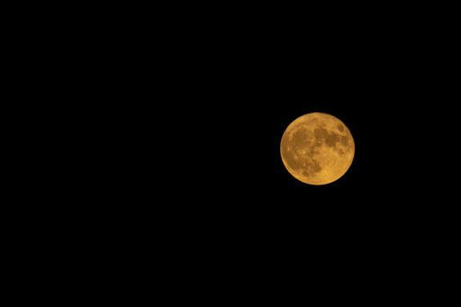 A yellow full moon in dark night sky