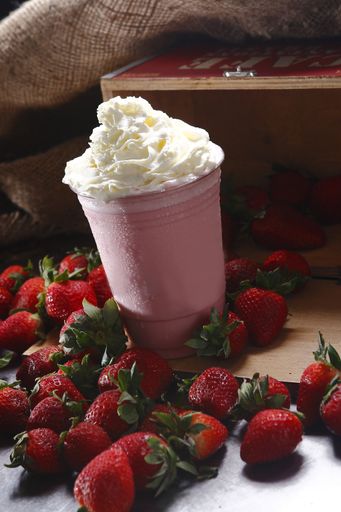 A close up shot of delicious strawberry milkshake with whipped cream on top