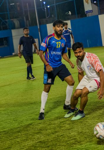 A vertical of a Southeast Asian player trying to defend from the opponent in a local football match in Kolkata, India