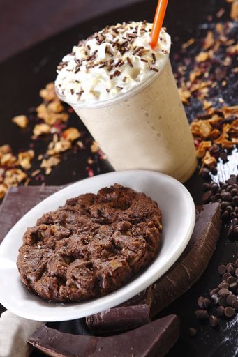 A close up shot of delicious milkshake with whipped cream on top and a chocolate cookie