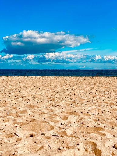 A vertical shot of a sandy beach against the blue Baltic sea in Gdynia, Poland