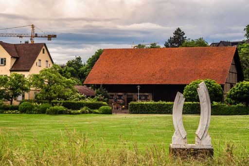 A beautiful shot of a sculpture on green lawn against rural houses in Germany on a cloudy day