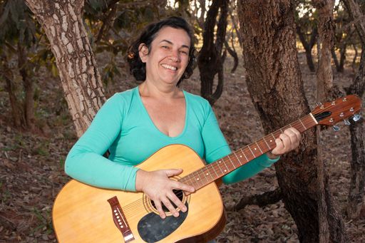 Happy Mature women playing and singing her acoustic guitar in the park