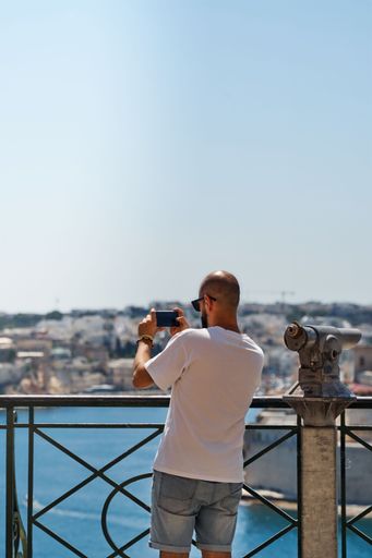 A male taking a picture of a beautiful view of Malt from a balcony